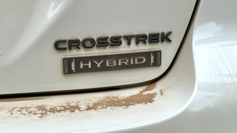 Un gros plan de l'insigne arrière sur l'hybride White Crosstrek très poussiéreux