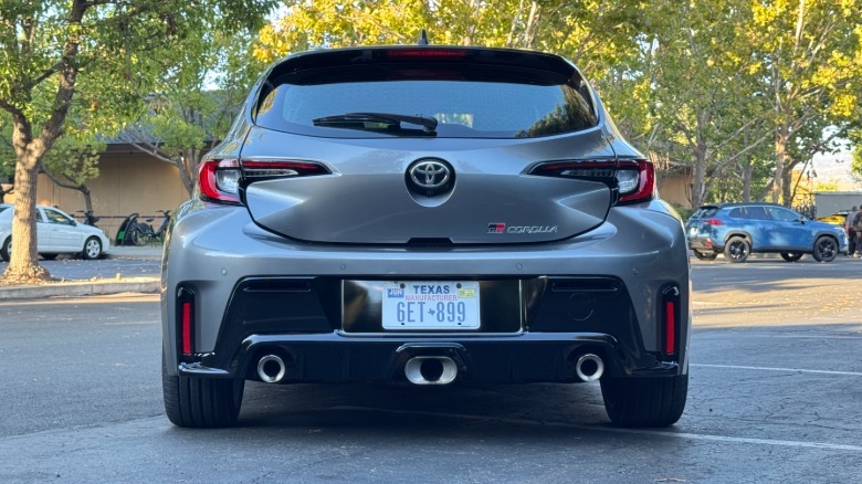 Une photo de l'arrière d'une Corolla en argent dans un parking devant les arbres