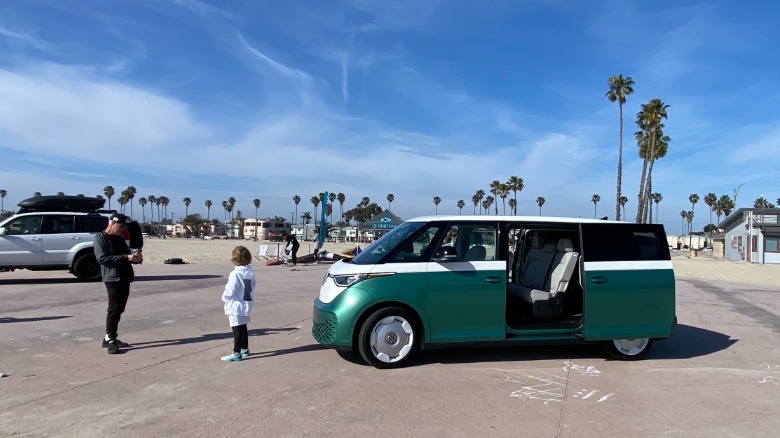Un père prenant une photo de son fils devant le buzz vert et blanc sur la plage